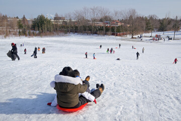 Mother and daughter playing toboggan.  Winter, outside, healthy lifestyle. - obrazy, fototapety, plakaty