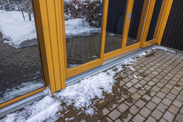 Exterior view of glass wall of modern house and icy paving slabs. Sweden. 