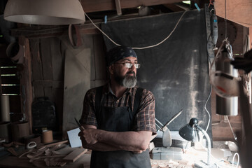 Spoon craft master in his workshop with handmade wooden products and tools