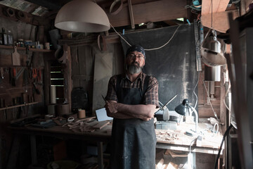 Spoon craft master in his workshop with handmade wooden products and tools