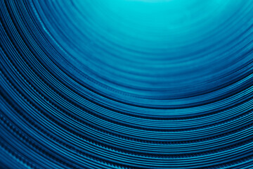 Ridged texture. Blur glow background. Embossed steel gear wheels. Defocused neon blue color light reflection on dark curved corrugated abstract overlay.