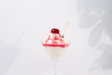 Helado de crema con jarabe de cereza. Sombras suaves de hojas en la pared postre de verano