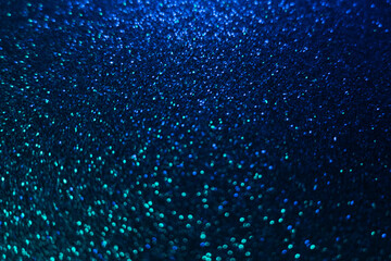 Color bokeh glow. Glitter background. Wet asphalt reflection. Defocused neon blue green light shiny sparkles round flecks texture on dark black abstract overlay.