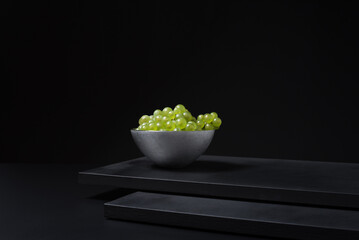 Racimo de uvas para vino blanco en un recipiente sobre fondo negro	