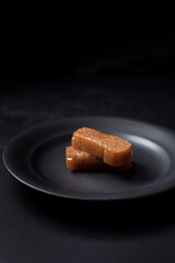 Dulce pasta de gelatina de membrillo dorado sobre una placa de madera negra	