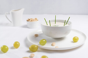 Crema de almendras, sopa fría española. Ajo blanco de Málaga con almendras y uvas en un recipiente blanco sobre una mesa blanca	