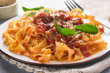 Tagliatelle pasta with meatballs in tomato sauce and thyme in sauce on light grey slate, stone or concrete background. Traditional Italian dish and cuisine. Top view with copy space.