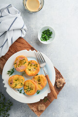 Egg muffins with green onions, bacon, cheese and tomatoes on white plate on light background. Healthy high protein and low carb breakfast, ready to eat.