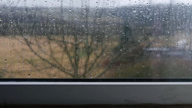 Timelapse of raindrops on window view of rural scene