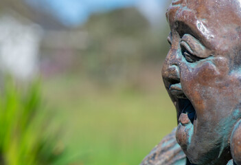 Fototapeta na wymiar Closeup of face on smiling Hotei Buddha statue with space for copy