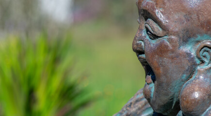 Closeup of face on smiling Hotei Buddha statue with space for copy