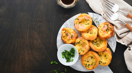 Delicious egg muffins with green onions, bacon, cheese and tomatoes on wooden board on old wooden rustic background. Healthy high protein and low carb breakfast. Homemade food.