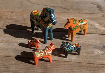 A group of Swedish wooden Dala horses in various colors on a rustic wooden tabletop