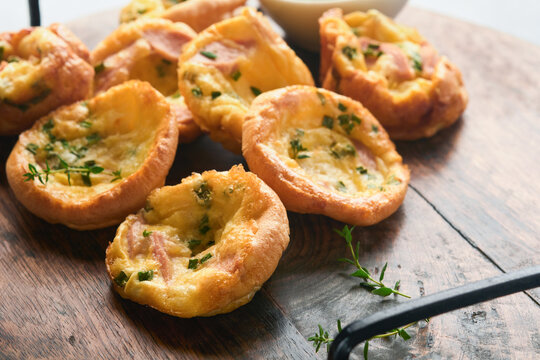 Delicious egg muffins with green onions, bacon, cheese and tomatoes on wooden board on light background. Healthy high protein and low carb breakfast. Homemade food.