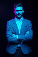 Young handsome model posing in a studio in a trendy neon light. Fashionable man in a stylish suit....