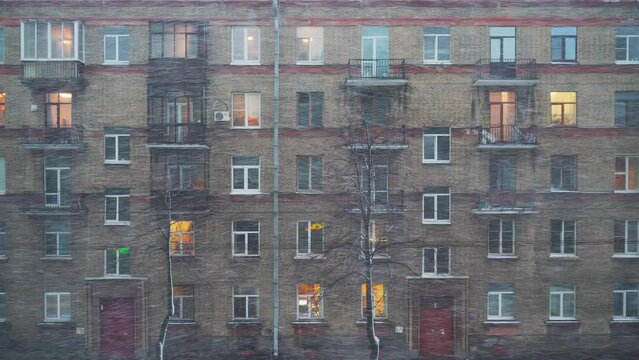 4k, view of a multi-storey residential building during heavy snowfall and wind