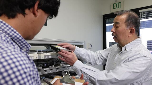 The person in charge explaining in front of the product and the young businessman receiving the explanation 