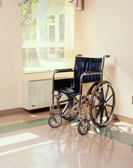 Fototapeta na wymiar Wheel chair in corner of institutional room with window