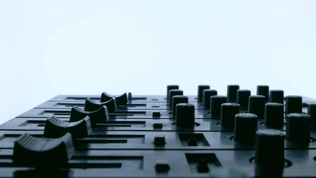 Silhouette of Professional sound engineer or music DJ balancing volume of audio inputs of digital audio mixer. Hand pushing a fader of a mixing console. 