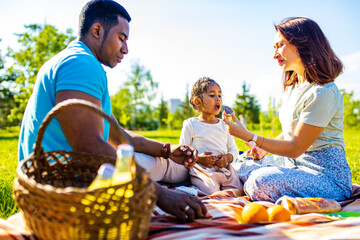 latin hispanic dad and european mom with cute child at picnic in sunny day