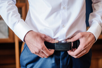 The groom tightens his belt. A man holding his hands on his belt