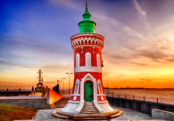the historical lighthouse "Kaiserschleuse Ostfeuer" (Pingelturm) in Bremerhaven, Germany in front of colorful kitschy sunset sky