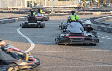 People driving karting cars on go-kart racing tracks outdoors