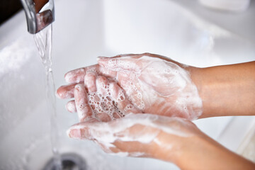 Fototapeta premium Good hygiene - a great habit. A cropped shot of a young woman washing her hands in her bathroom.