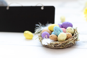 easter holiday, easter multicolored eggs in a nest, a sign for text, copy space