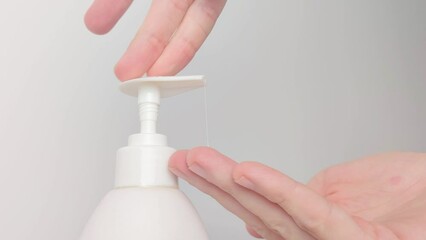 Taking liquid soap from push dispenser. Male hand push the dispenser.
