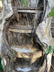 Closeup of hollowed out wood tree trunk with artificial waterfall for garden or home decoration