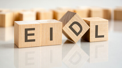 four wooden blocks with the letters EIDL on the bright surface of a gray table, business conceptual word collected of of wooden elements with the letters