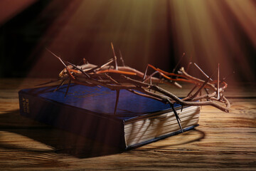 Fototapeta na wymiar Holy Bible and crown of thorns on table against dark background