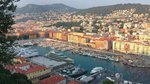 A lot o motor boats and luxury meg yachts are moored in port of Nice - France at sunset, mooring ropes go into the amazing azure water, prows of motor boats in a row, roofs of orange color