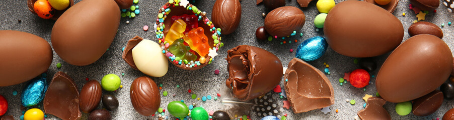 Tasty chocolate Easter eggs with different candies on grunge background