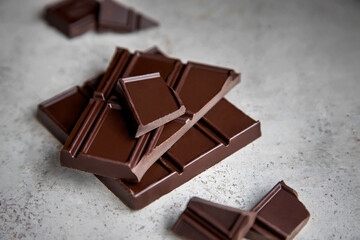 Broken bar of dark chocolate on a gray stone background