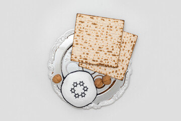 Passover Seder plate, flatbread matza, walnuts and kippah on light background