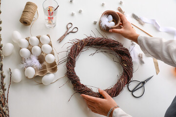 Woman making Easter wreath on light table, closeup