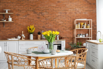 Teapot, cups, tulips and greeting card with text HAPPY WOMEN'S DAY on dining table in kitchen
