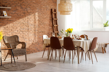 Stylish setting on dining table served for Easter celebration in light room interior