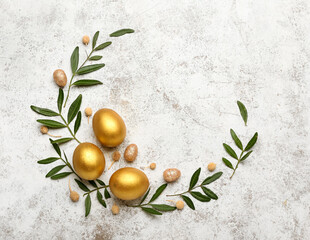 Stylish wreath with golden Easter eggs and leaves on light background