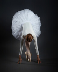 attractive ballerina stands on her fingertips. photo shoot in the studio on a dark background