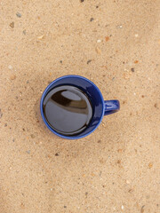 blue coffee mug in the sand at the beach