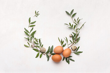 Stylish Easter wreath made of leaves and eggs on light background