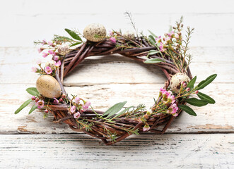 Easter wreath with leaves and flowers on light wooden background