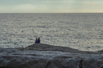 Fototapeta na wymiar couple on rocks overlooking the ocean horizon