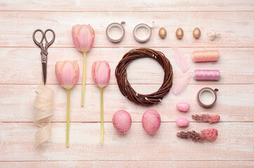 Composition with Easter wreath, flowers, eggs and scissors on color wooden background