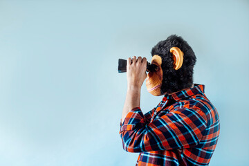 Man with monkey mask using binoculars.