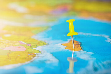 yellow pushpin on the world map. The concept is that travel is available anywhere in the world, delivery of goods to any country. Close-up, horizontal photo.
