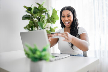 young African American businesswoman working at laptop at home office with credit card on hand